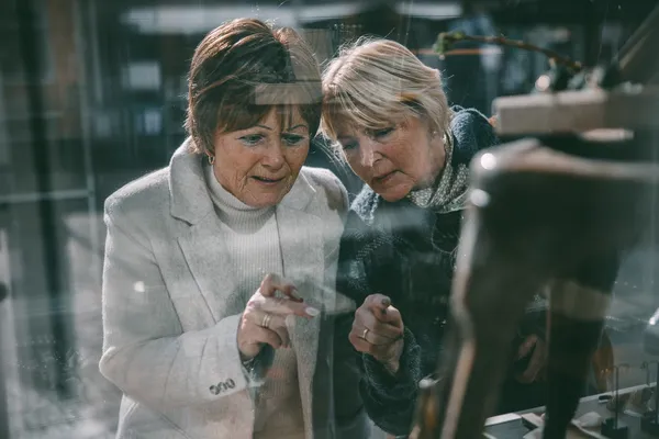 To damer ser igjennom vindu og peker.