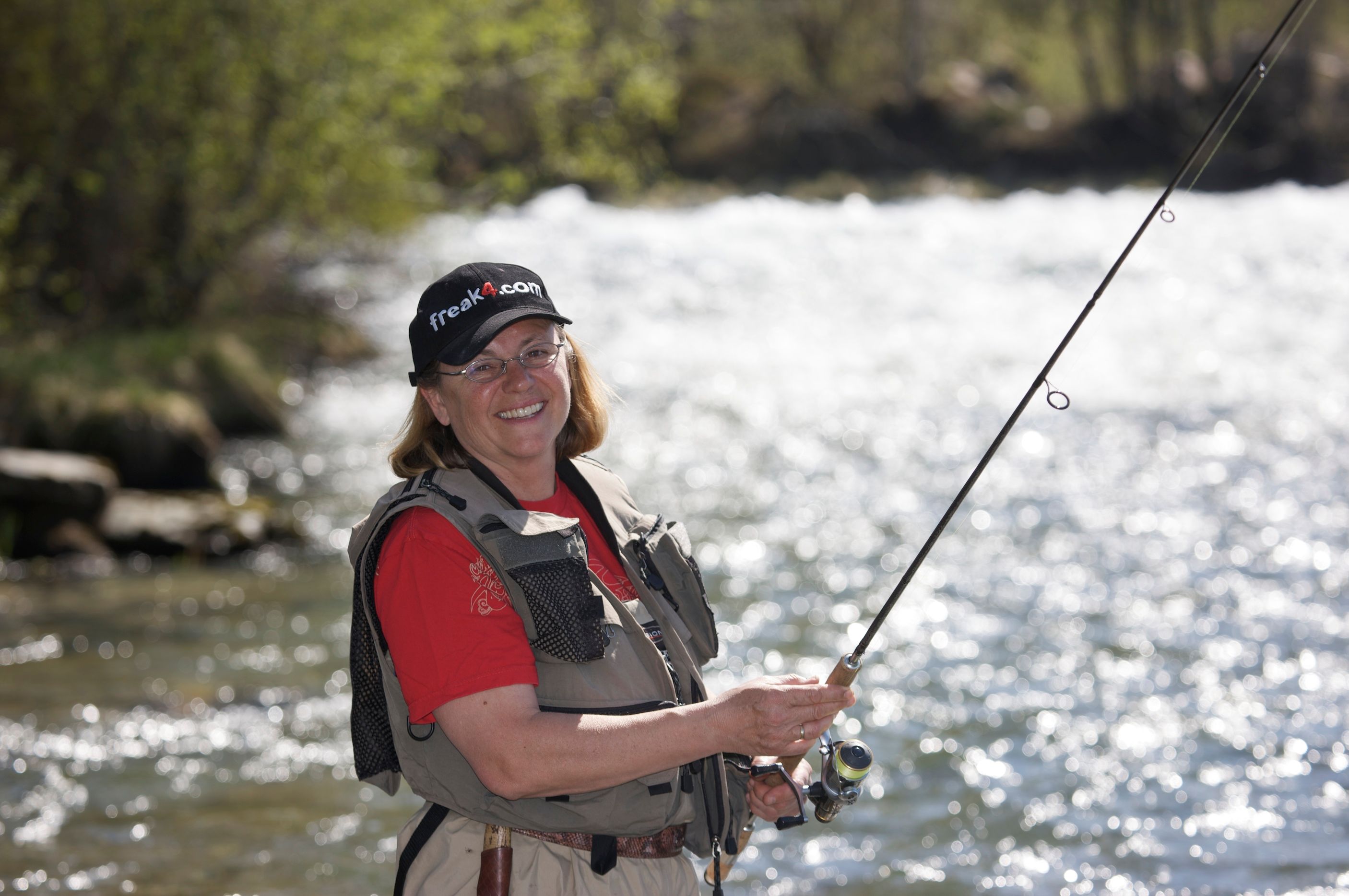 a woman is fishing in a river with a fishing rod .