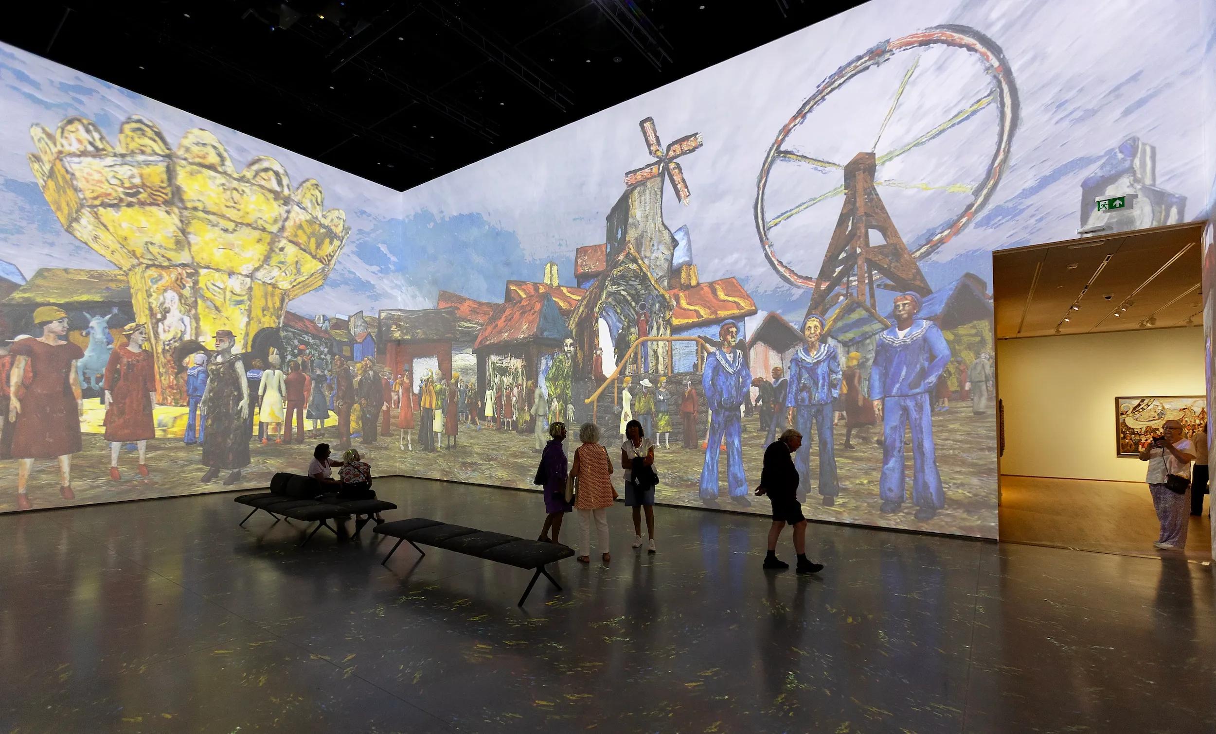 Visitors walk around an art museum with large, colorful projections of paintings on the walls.