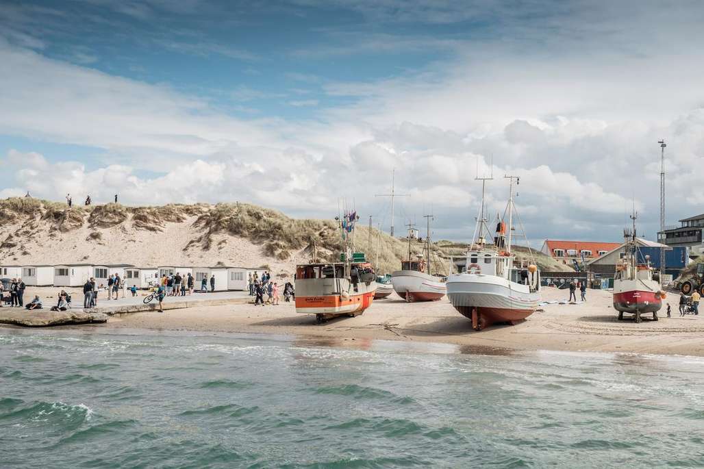 Strand med badehus og fiskebåter.