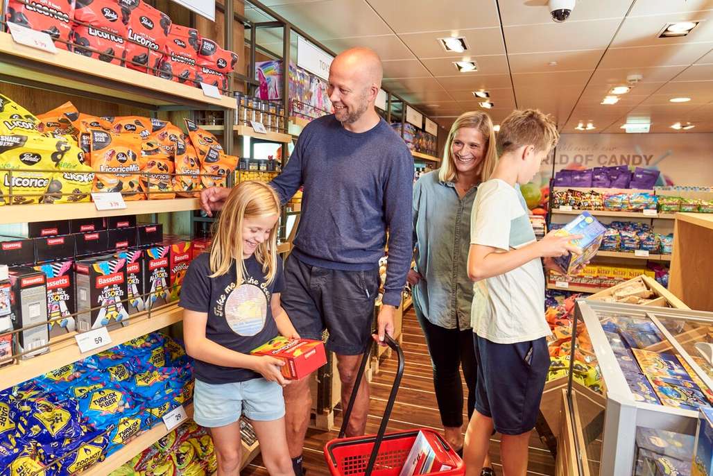 Familie hygger seg blant godterihyllene i taxfree-butikk.