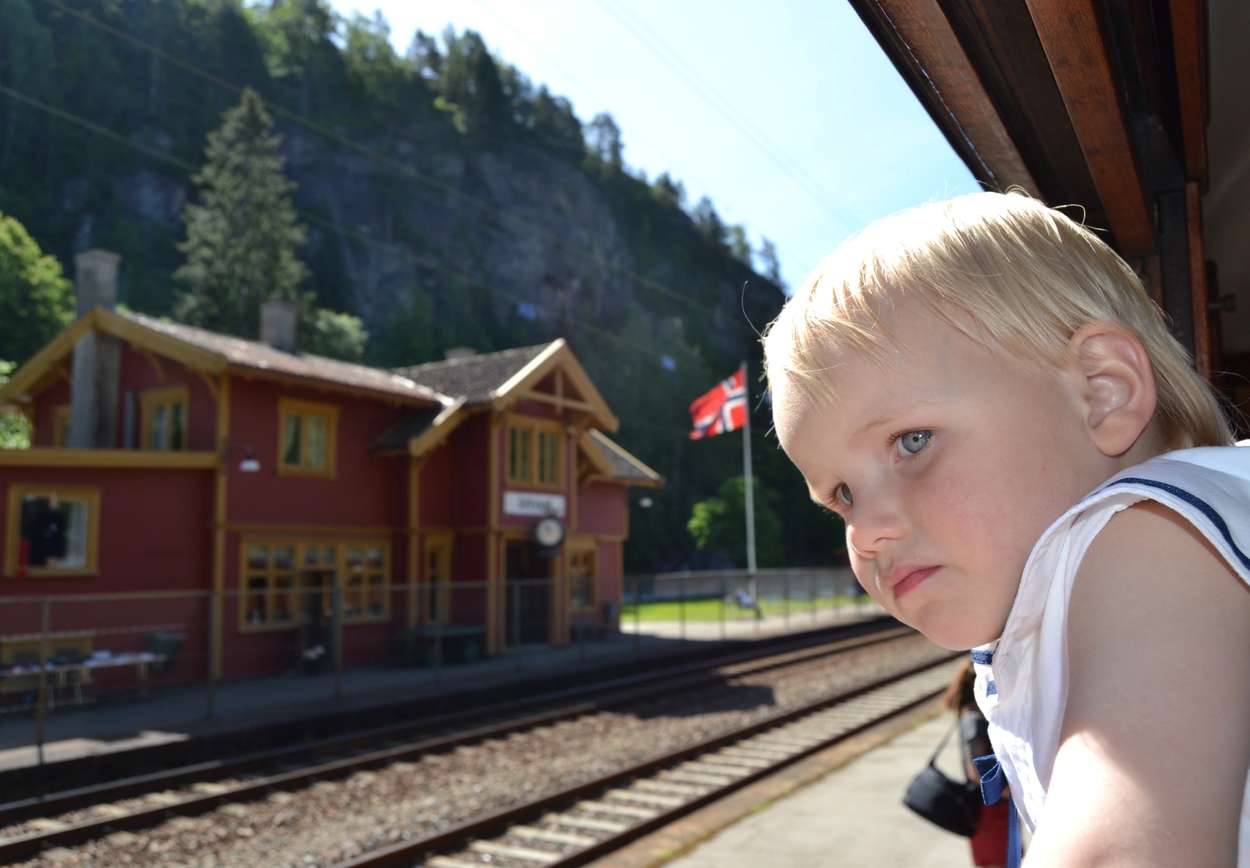 Kleiner Junge schaut aus dem Fenster eines Zuges in der Nähe eines Bahnhofs