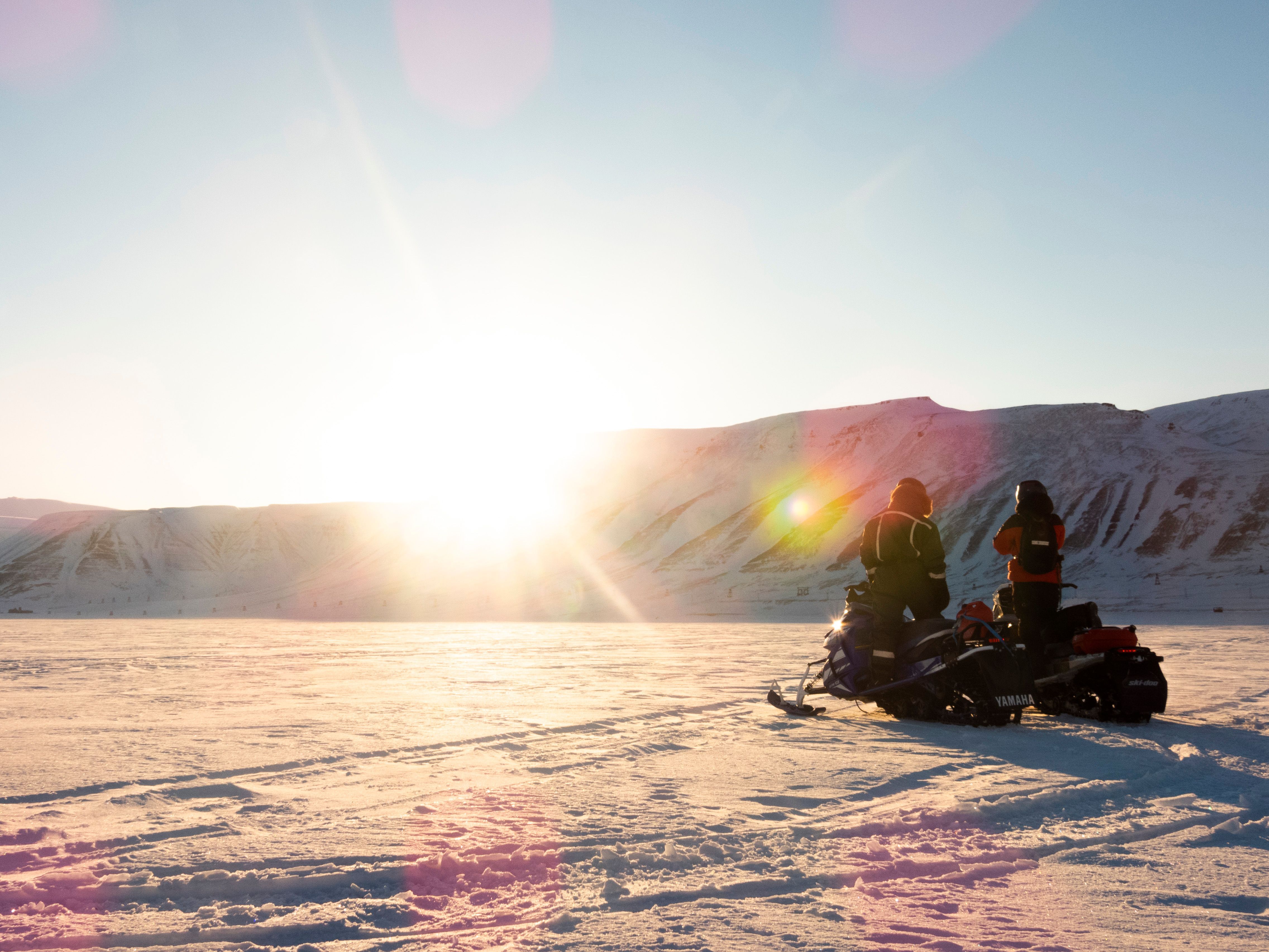 a group of people are riding snowmobiles in the snow .