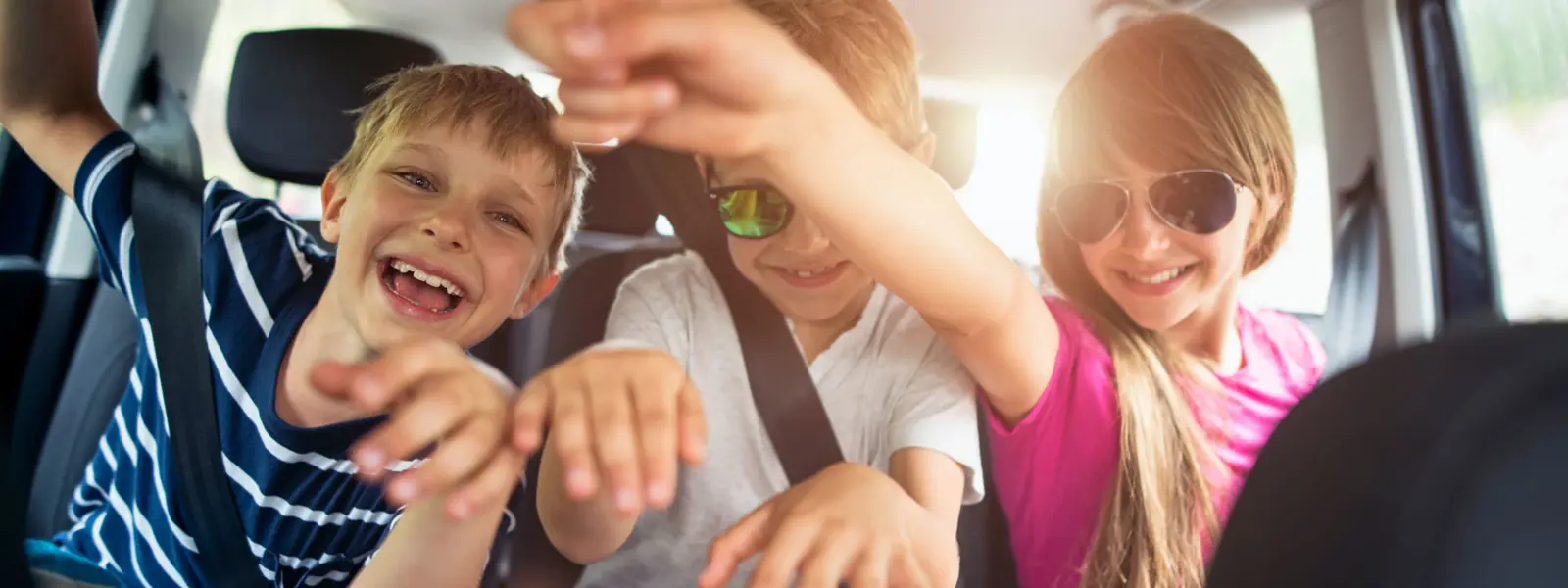 Tre barn i baksetet på en bil.