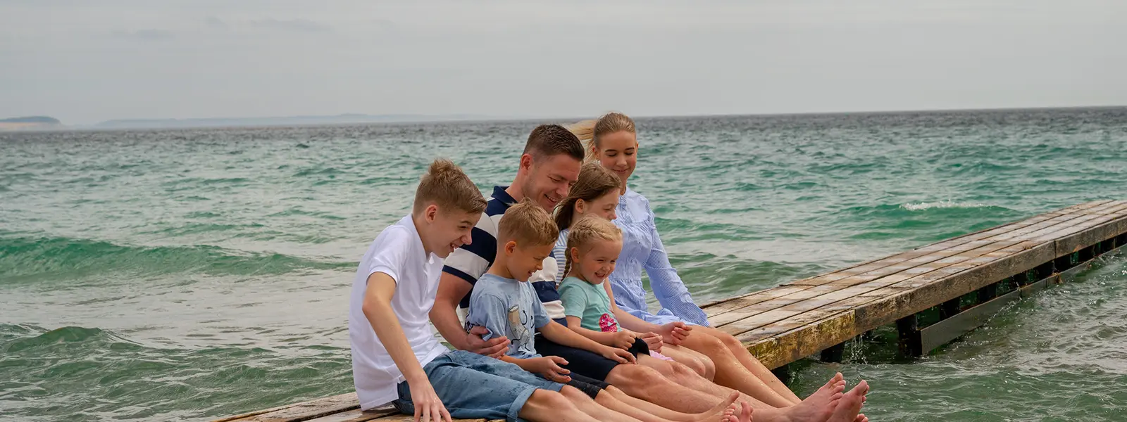 Familie som sitter på en brygge.