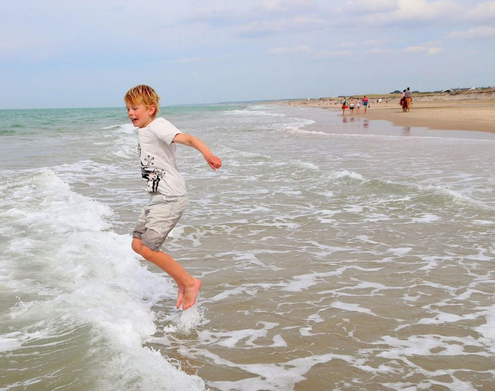 Barn leker i bølgene på stranden ved Skallerup