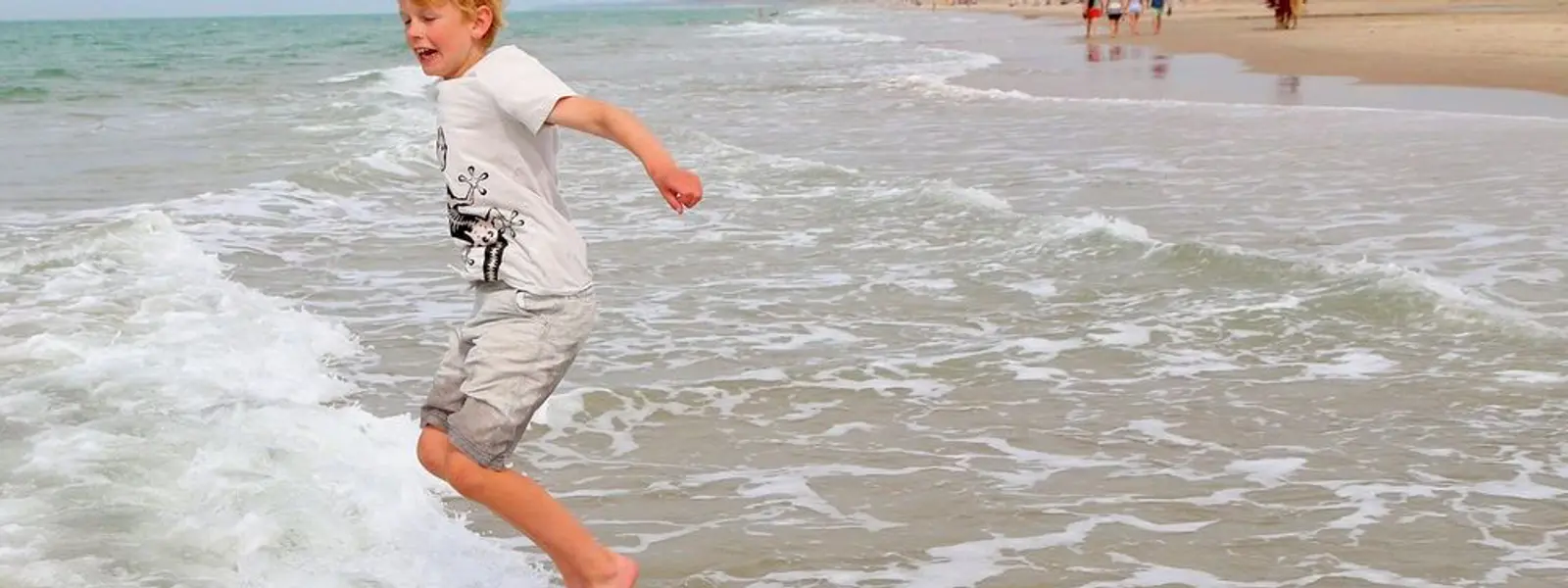 Barn leker i bølgene på stranden ved Skallerup