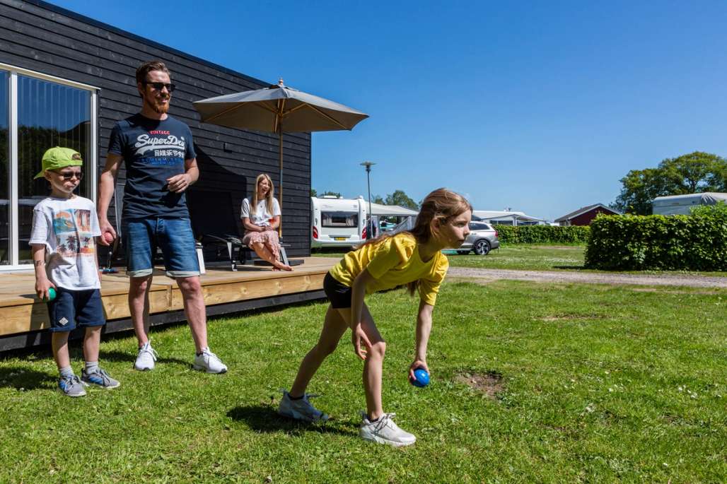 Familie på campingplass spiller spill på gresset.