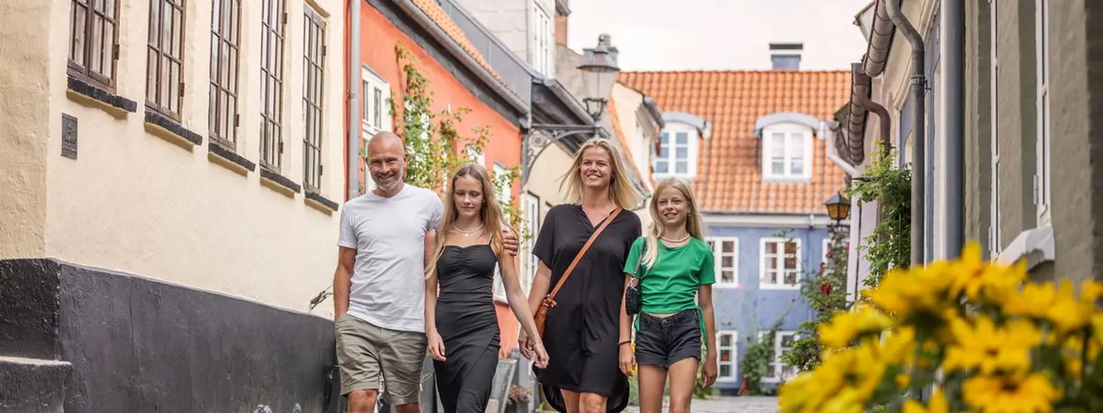 Familie på fire vandrer i en gate.
