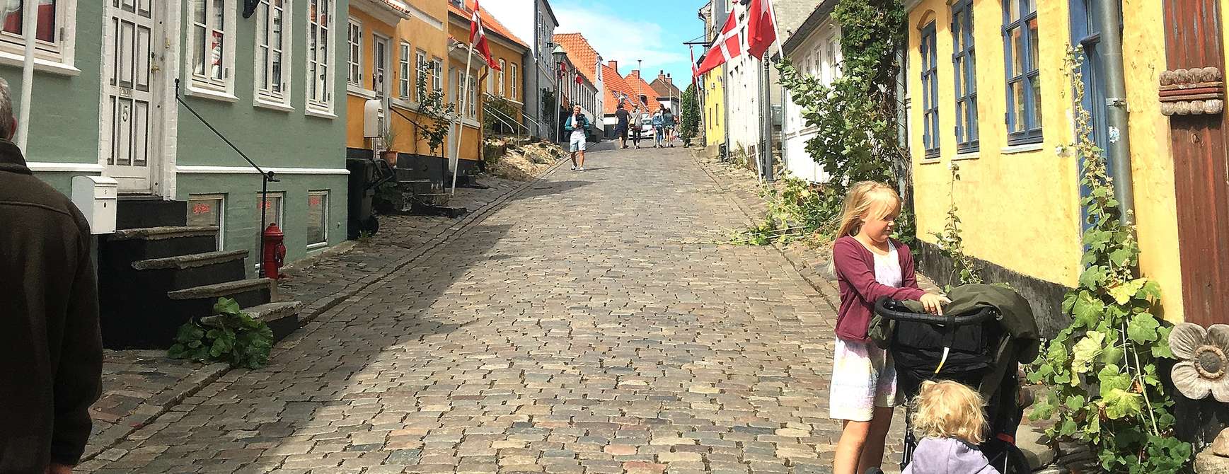 Familie nyter livet i en av de mange koselige brosteinsgatene i Danmark