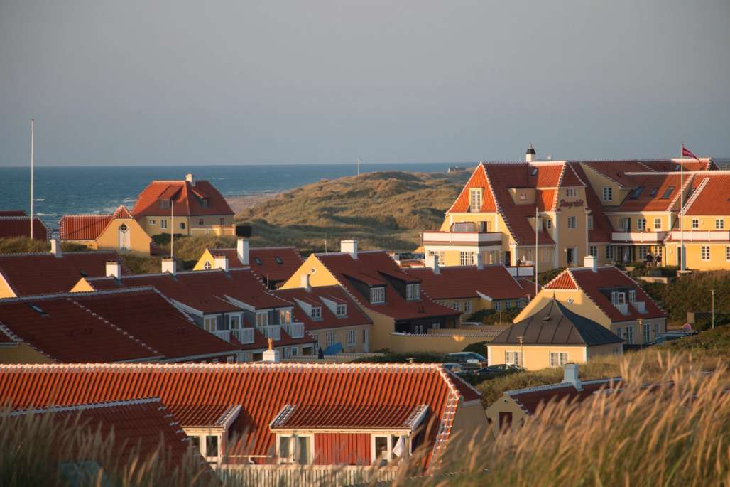 Gule hus i Skagen med havet i bakgrunnen.