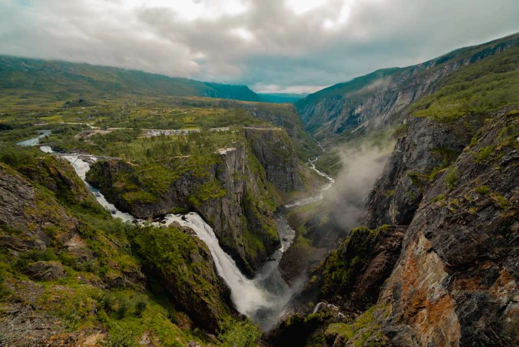 there is a waterfall in the middle of a canyon in the mountains .