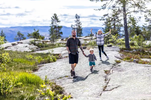 Vater und zwei Kinder auf einer Wanderung in der Berglandschaft.