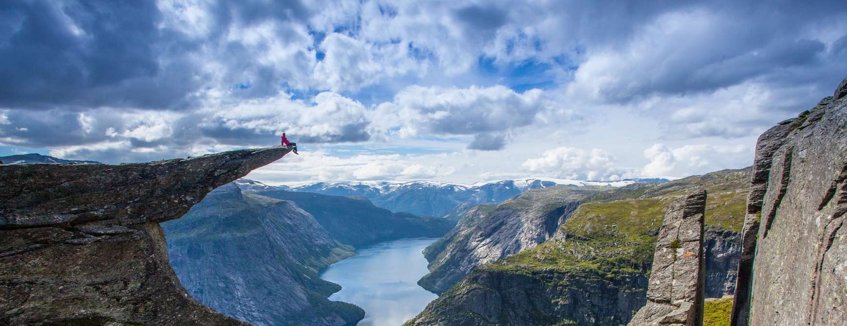 Person sitting at the edge of Trolltunga.
