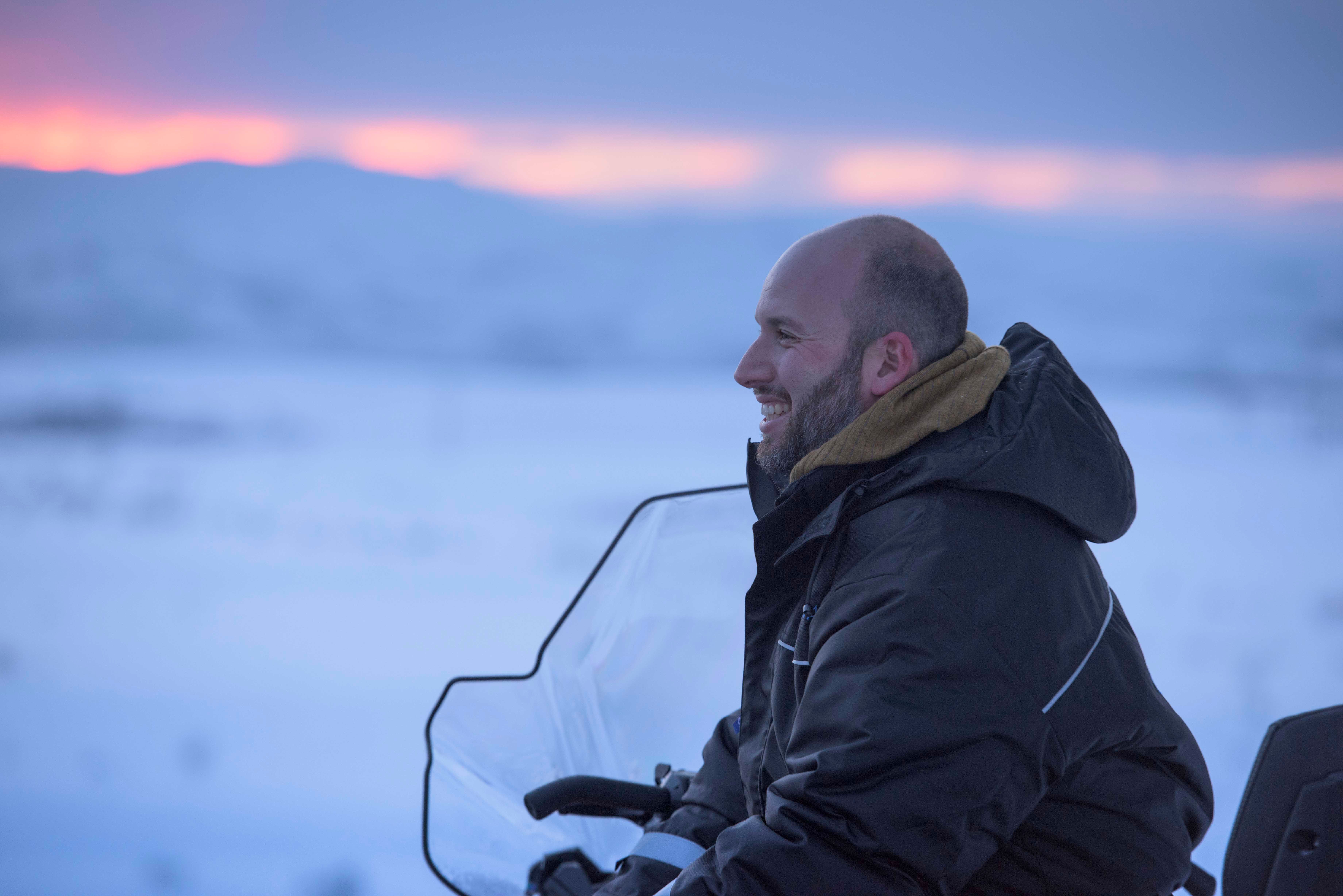 a man is sitting on a snowmobile in the snow .