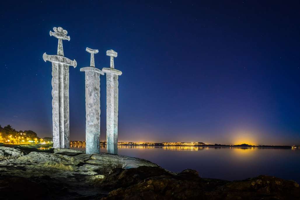 Das ikonische Sverd i fjell-Denkmal in Stavanger, Norwegen, nachts vom friedlichen Fjord beleuchtet.