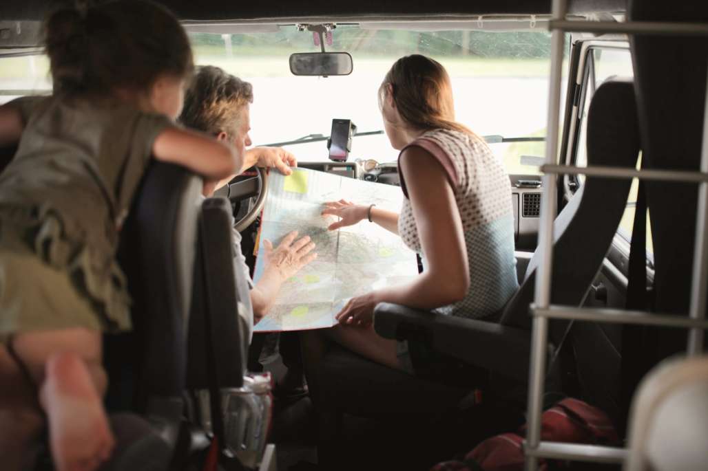 Familie sitter inne i en bil og ser i et kart.