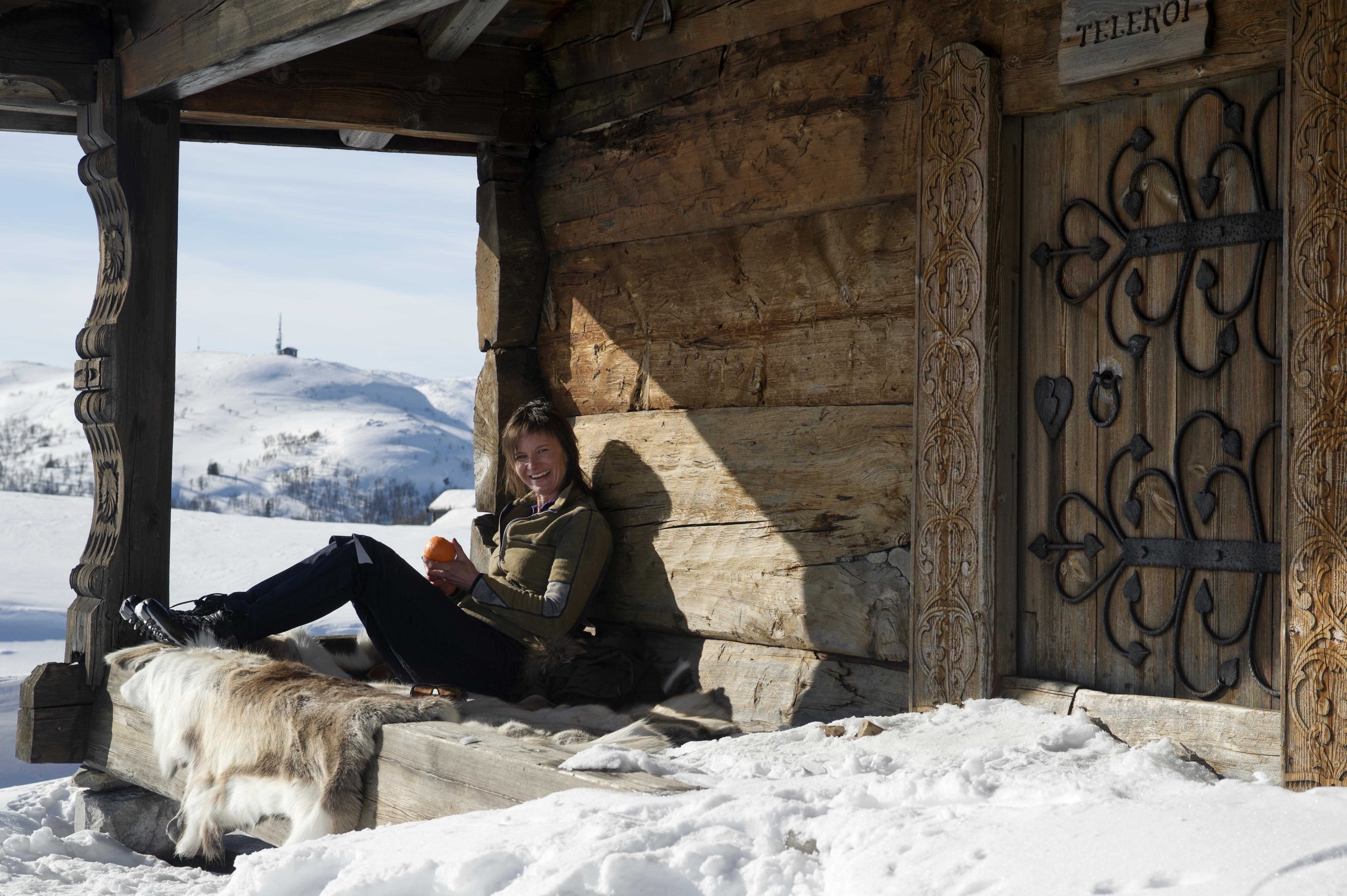 a woman is sitting on a wooden bench in the snow .