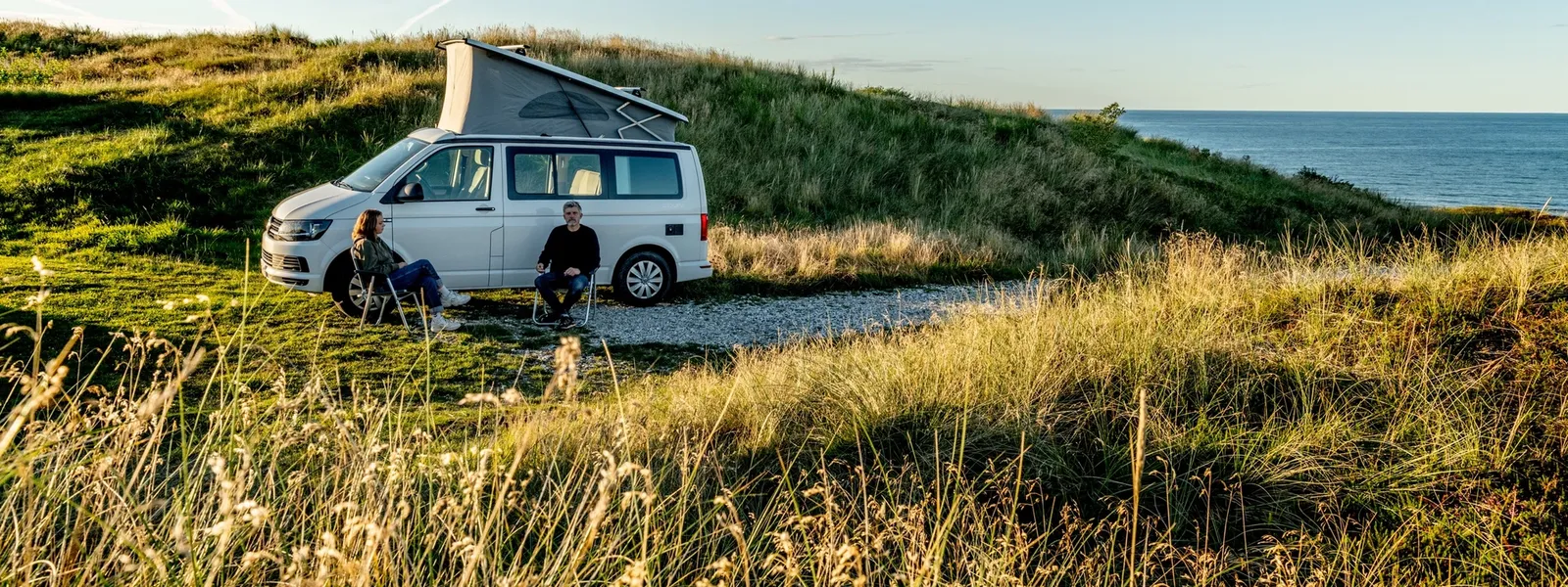 Par sitter utenfor en hvit vann på hver sin stol i idylliske omgivelser.