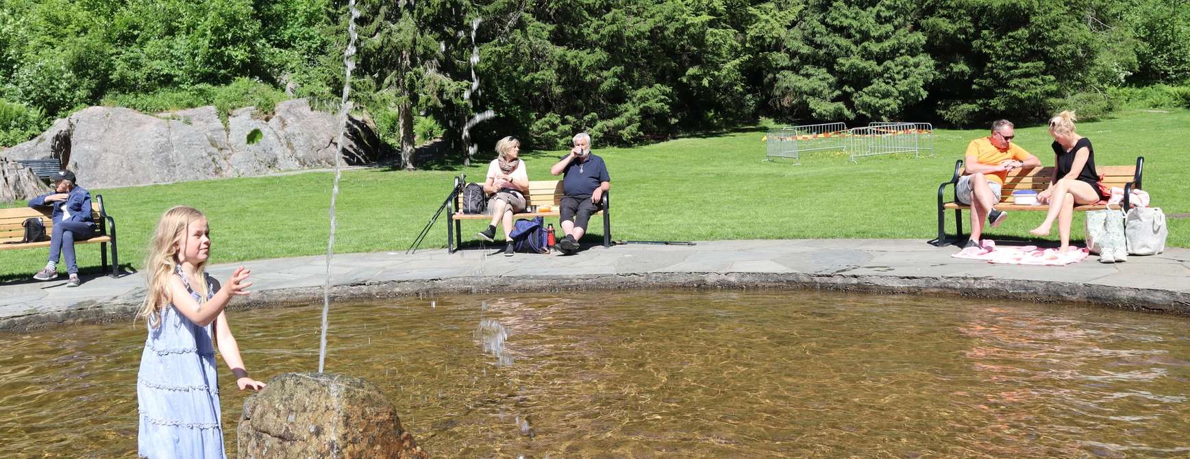 Personen sitzen auf Bänken um einen Brunnen herum