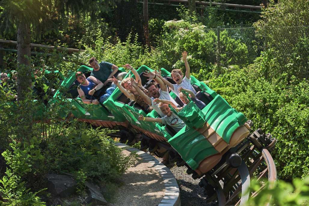 Grønn drage berg- og dalbane med folk som hygger seg.