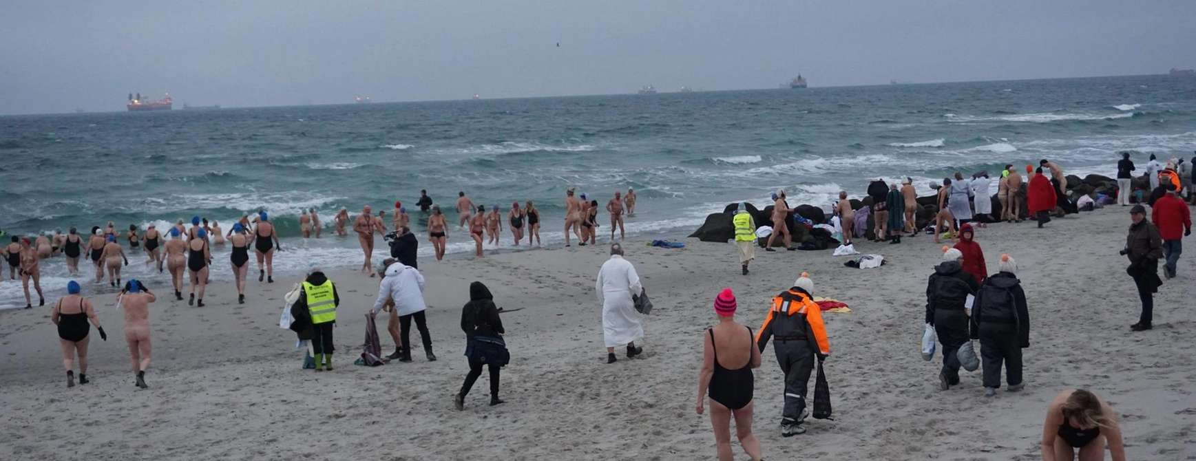 Strand om vinteren med mange badegjester. 