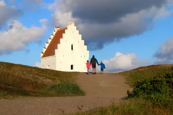 Bare toppen synes: Den tilsandede kirke, eller St. Laurentil kirke som den egentlig heter, ble oppført så tidlig som på 1300-tallet, men ettersom den ligger utsatt til for sandflukt, ble det til slutt for vanskelig for meningheten å grave seg frem til døren hver gang de skulle ha gudstjeneste. I 1775 ga de opp kampen og forlot kirken. I dag er den en turistattraksjon. Fra Skagen er det fantastiske tur- og sykkelstier frem til kirken. Foto: Fjord Line