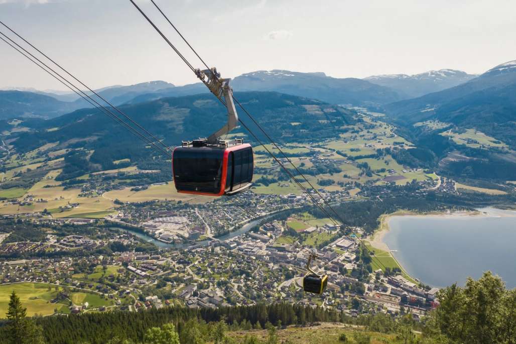 a cable car is flying over a city in the mountains .