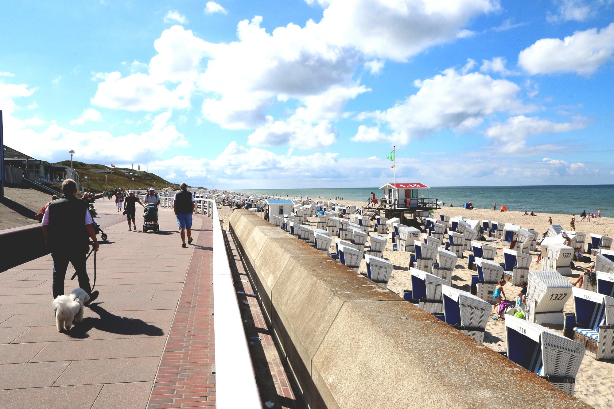 strandpromenade med sand, strandstoler og sjø