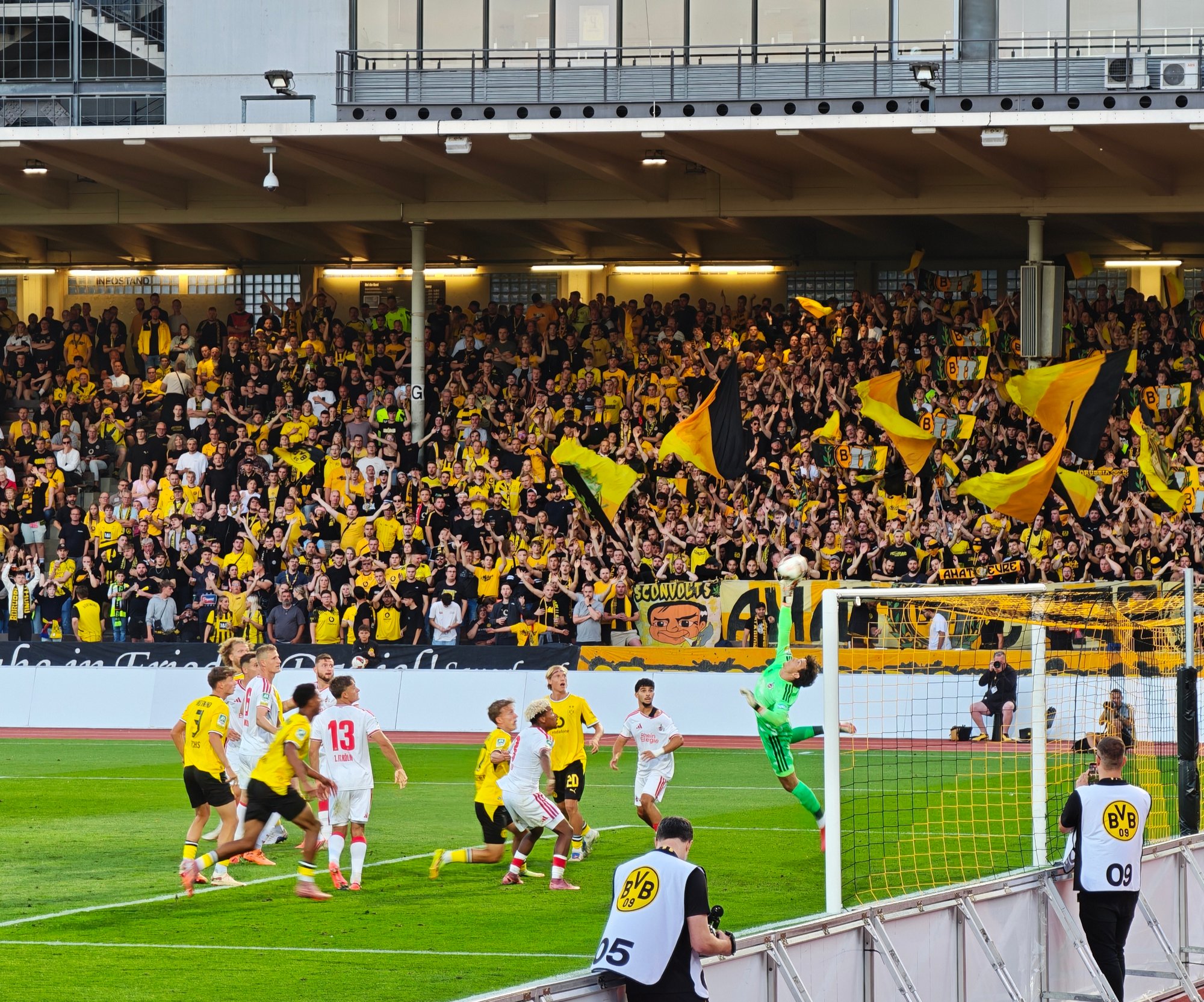 Spielszene zwischen BVB U23 und 1. FC Köln U21 vor der dicht besetzten Dortmunder Kurve in der Roten Erde.