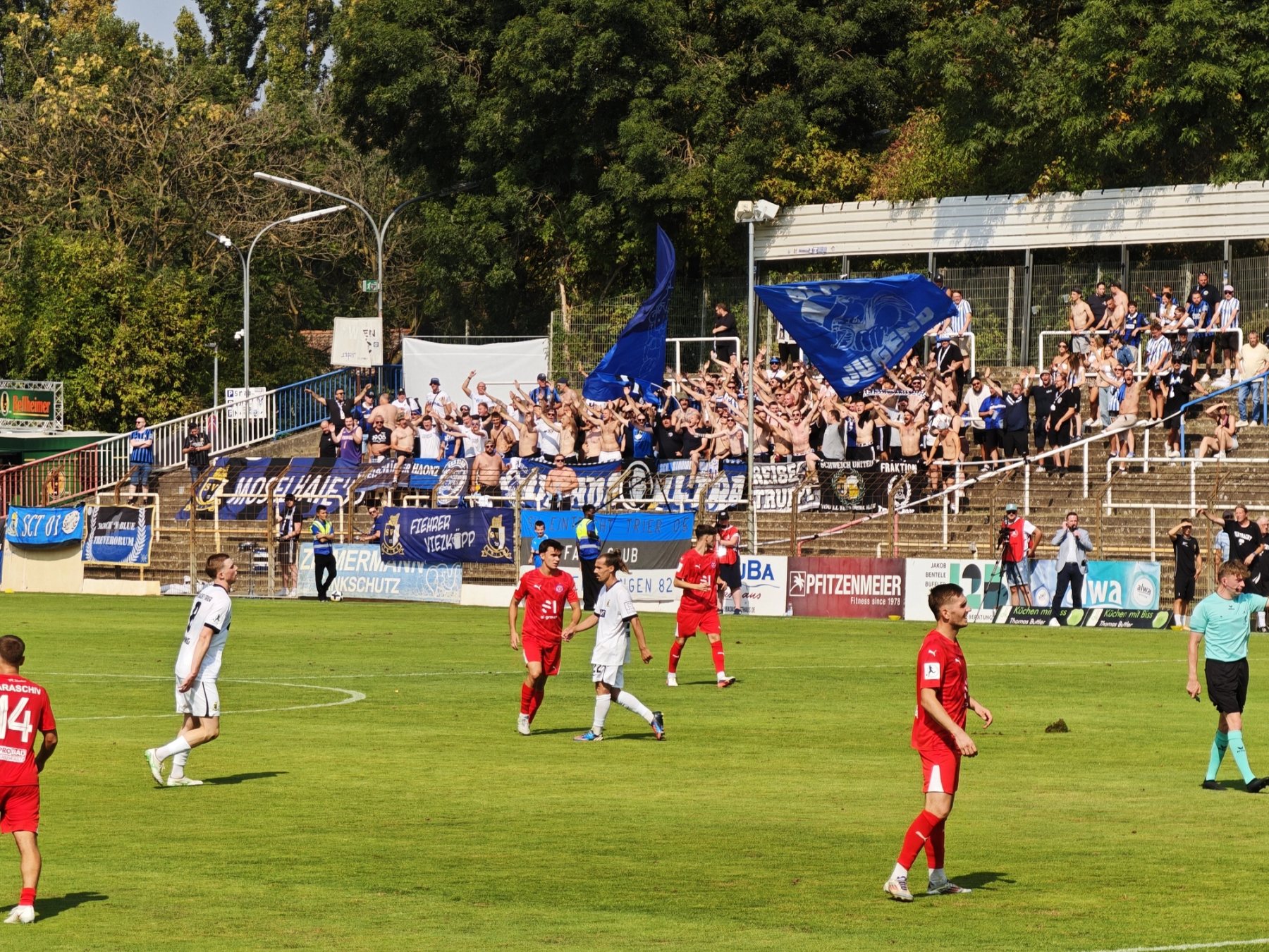 Aktiver Gästeblock von Eintracht Trier mit großen blau-schwarzen Fahnen im Rhein-Neckar-Stadion.