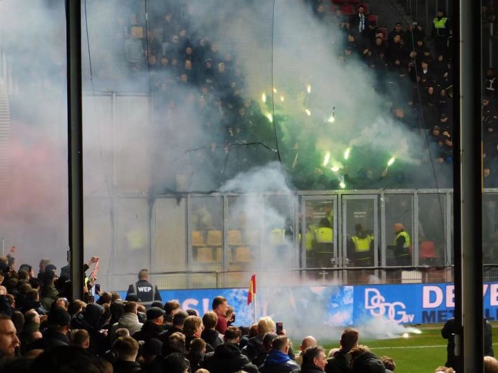 Pyrotechnik wird aus einem Gästeblock auf das Spielfeld geschossen, während dichter Rauch über den Tribünen hängt.