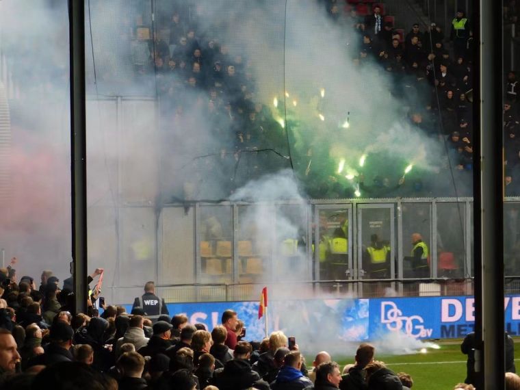 Pyrotechnik wird aus einem Gästeblock auf das Spielfeld geschossen, während dichter Rauch über den Tribünen hängt.