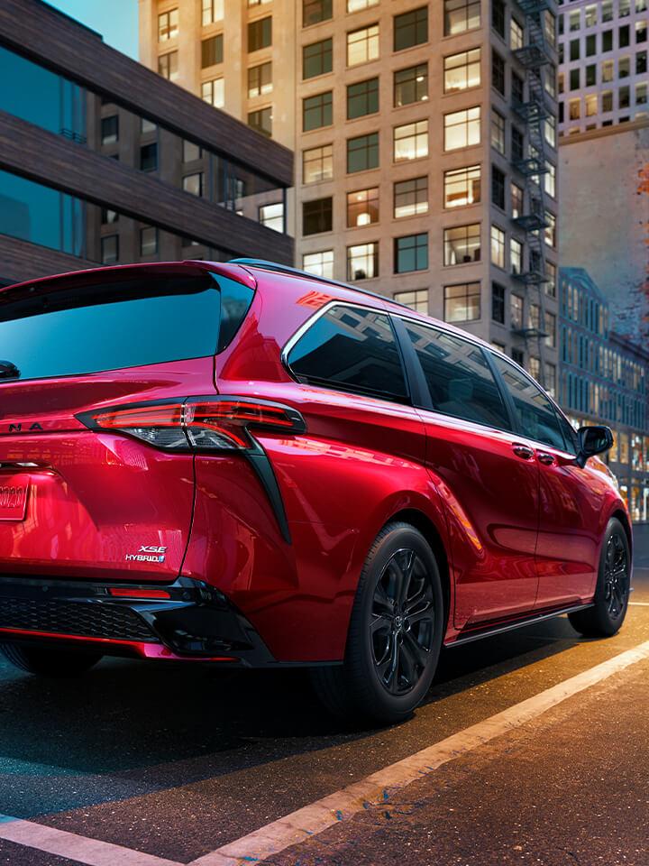 red Toyota Sienna driving down a city street