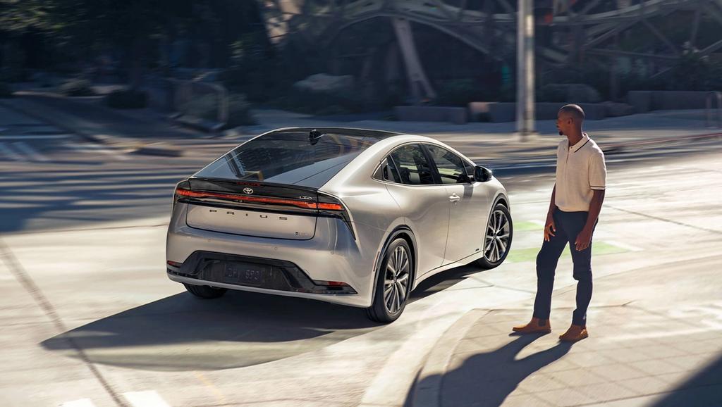man watching a 2023 Toyota Prius drive past on the street