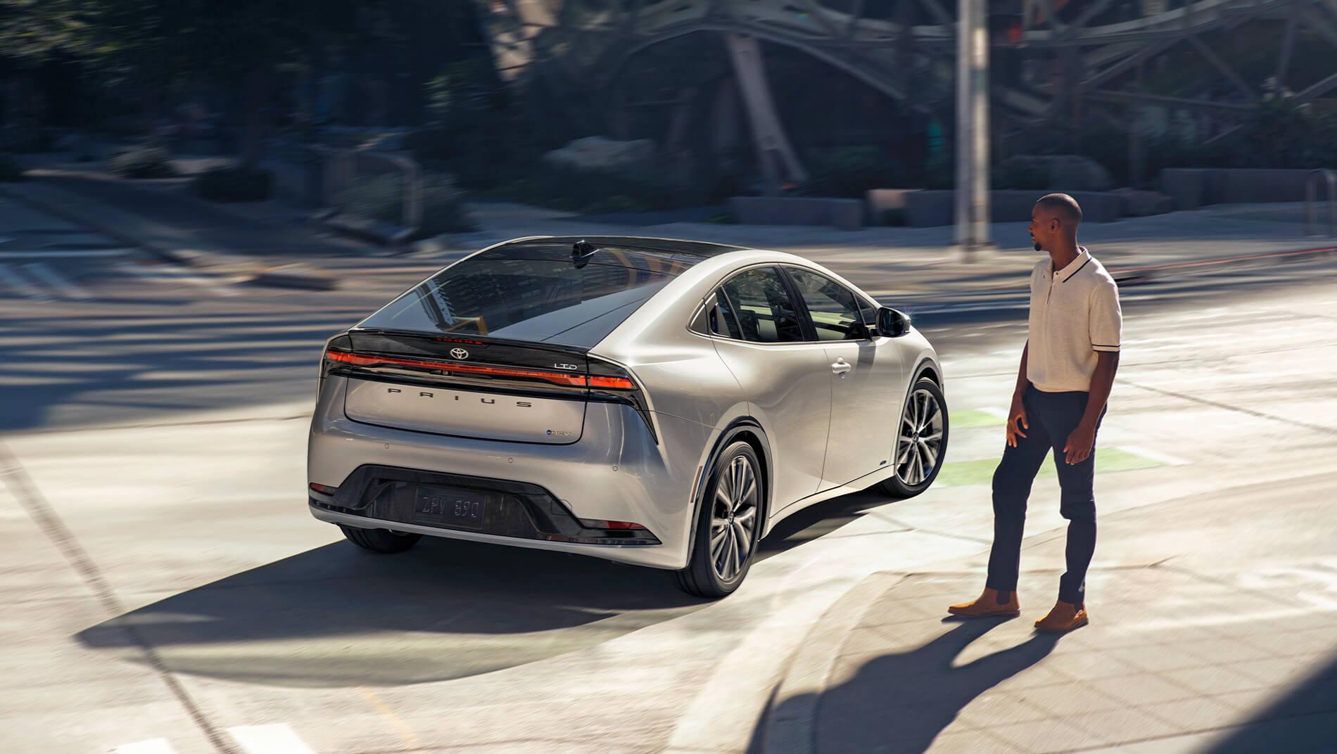 man watching a 2023 Toyota Prius drive past on the street
