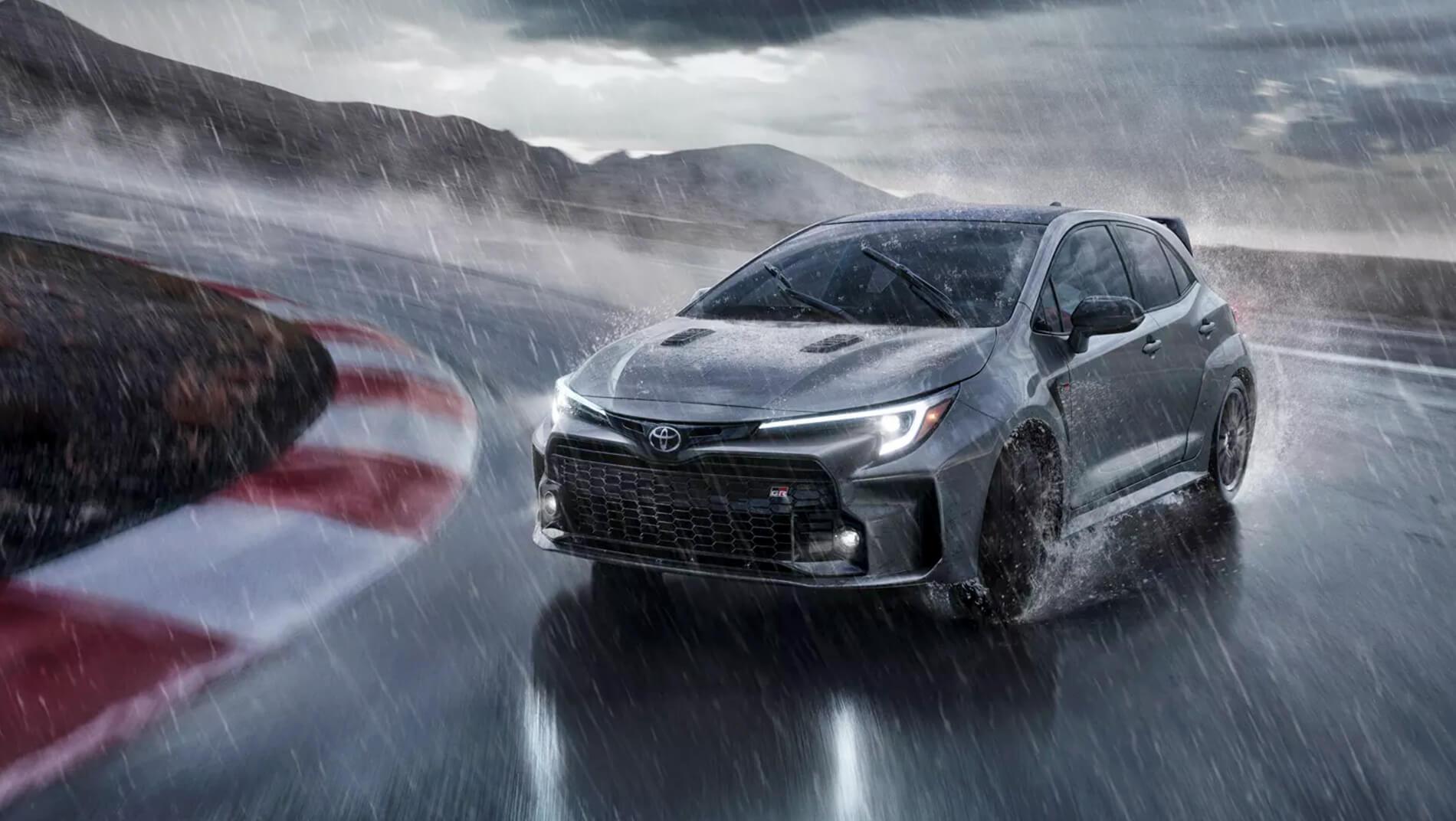 2023 Toyota GR Corolla driving around curve of race track in a storm and heavy rain