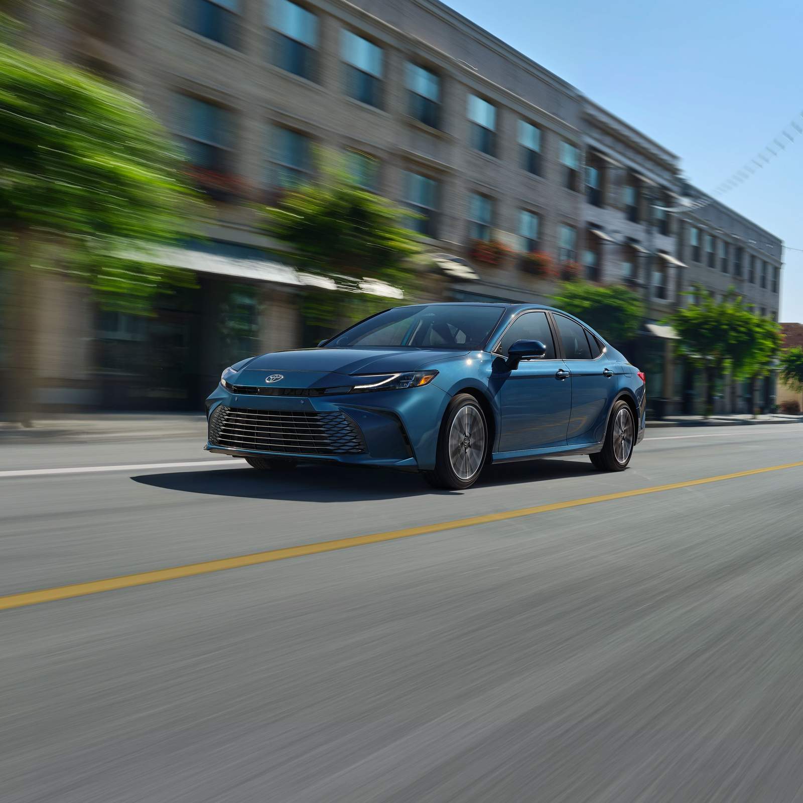 2025 Toyota Camry driving down the road.