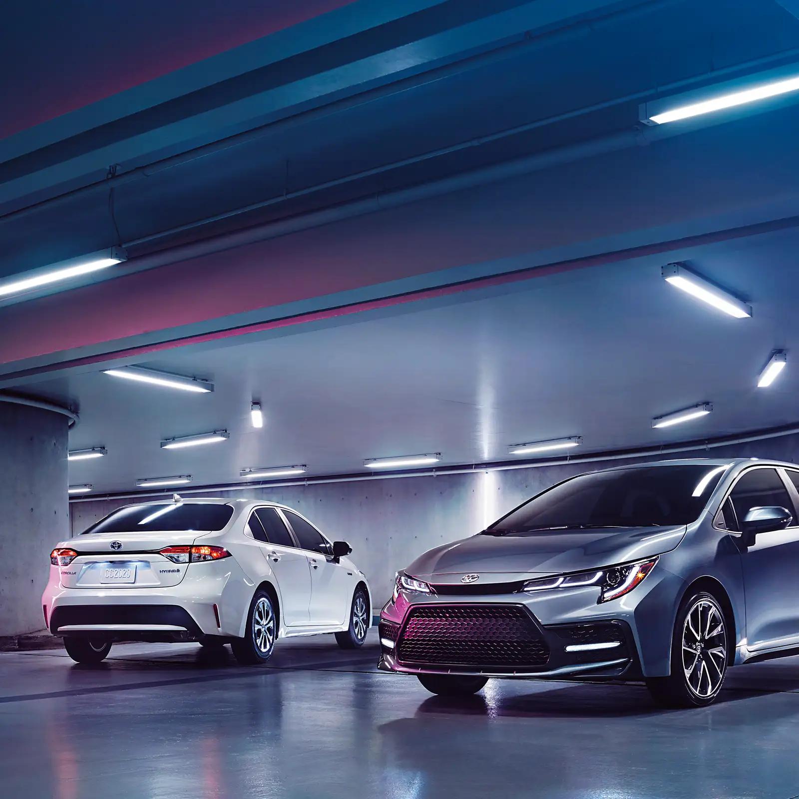 2 Toyota Corolla sedans parked in a well lit parking garage