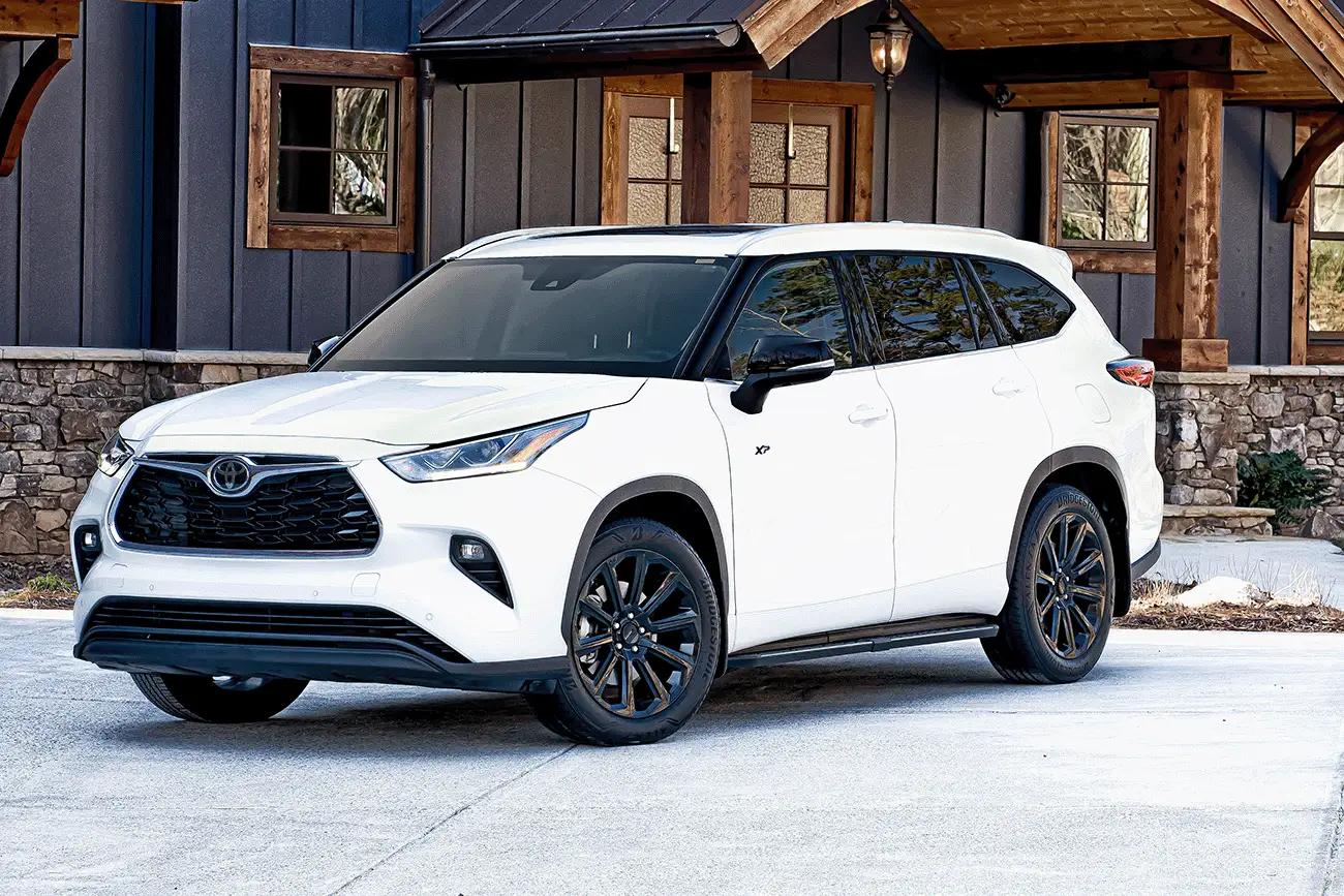 white Toyota Highlander XP XSeries upgraded toyota accessories package parked infront of a mountain cabin