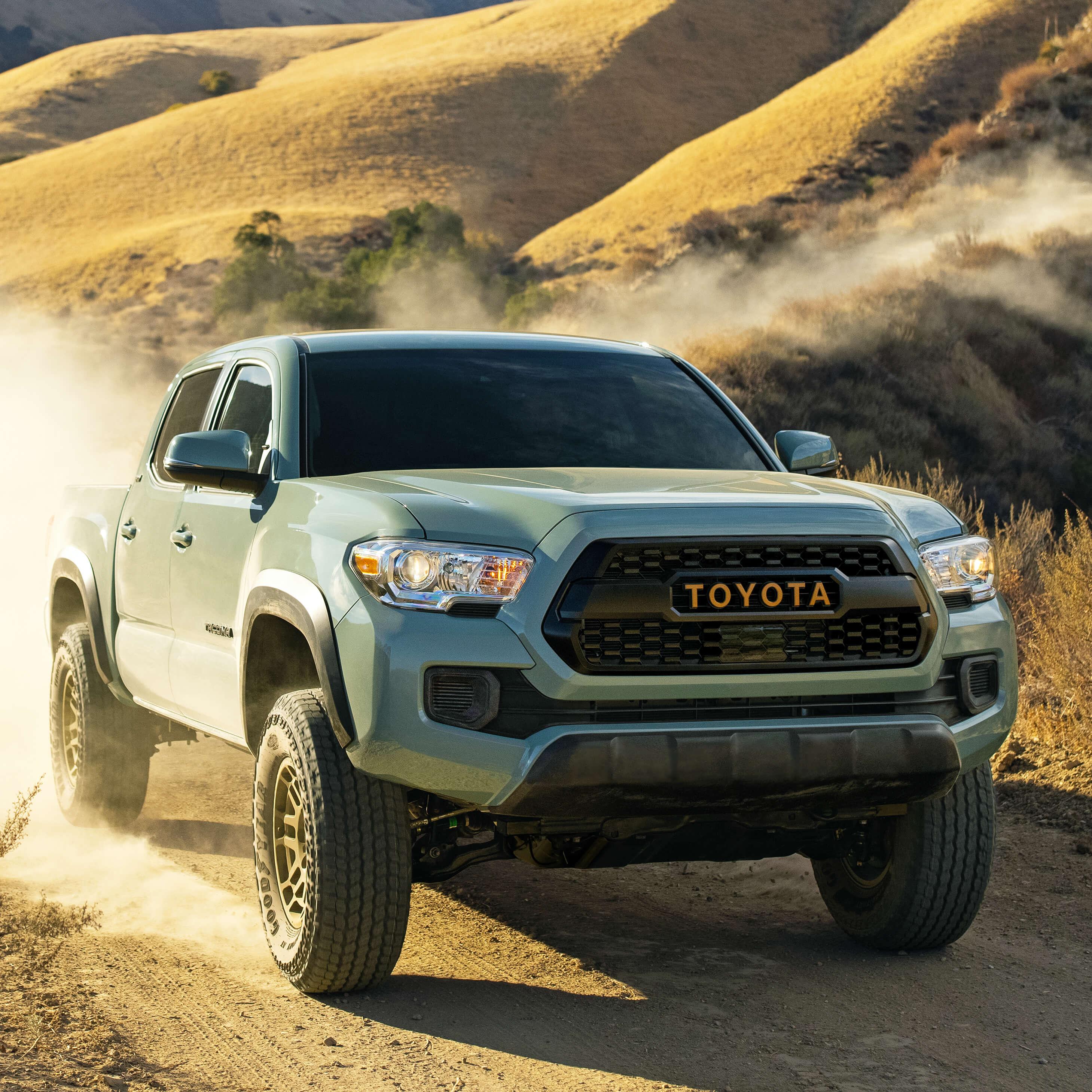 Toyota Tacoma driving down a dusty mountain road
