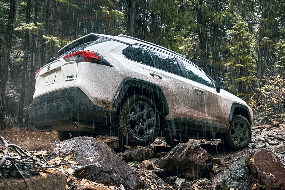 white Toyota RAV4 in the mountains climbing rocks and mud in the rain