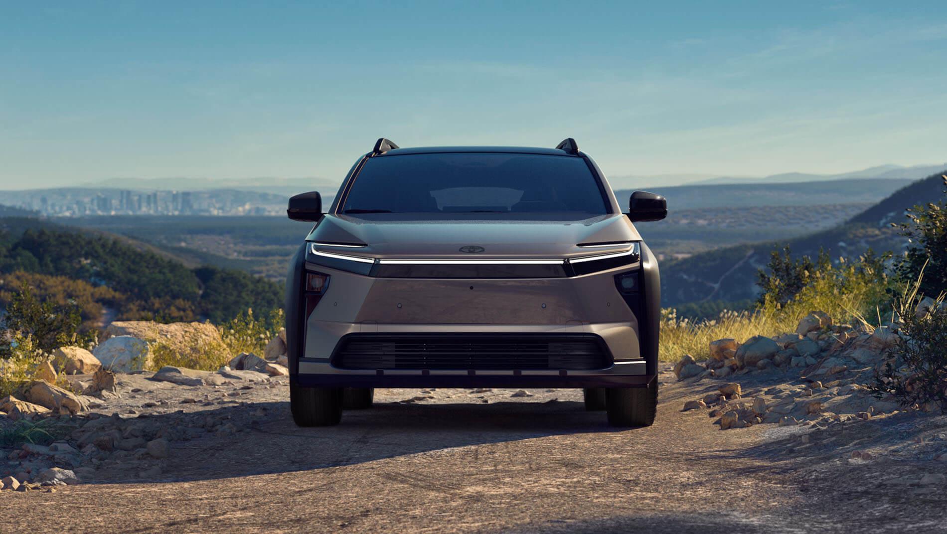 A brown toyota 2026 bzW SUV driving on a dirt road through a hilly landscape.
