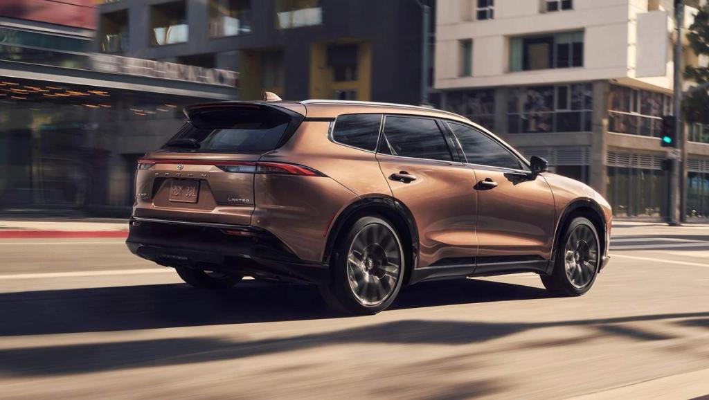 brown 2025 Toyota Crown Signia Hybrid driving down a city street