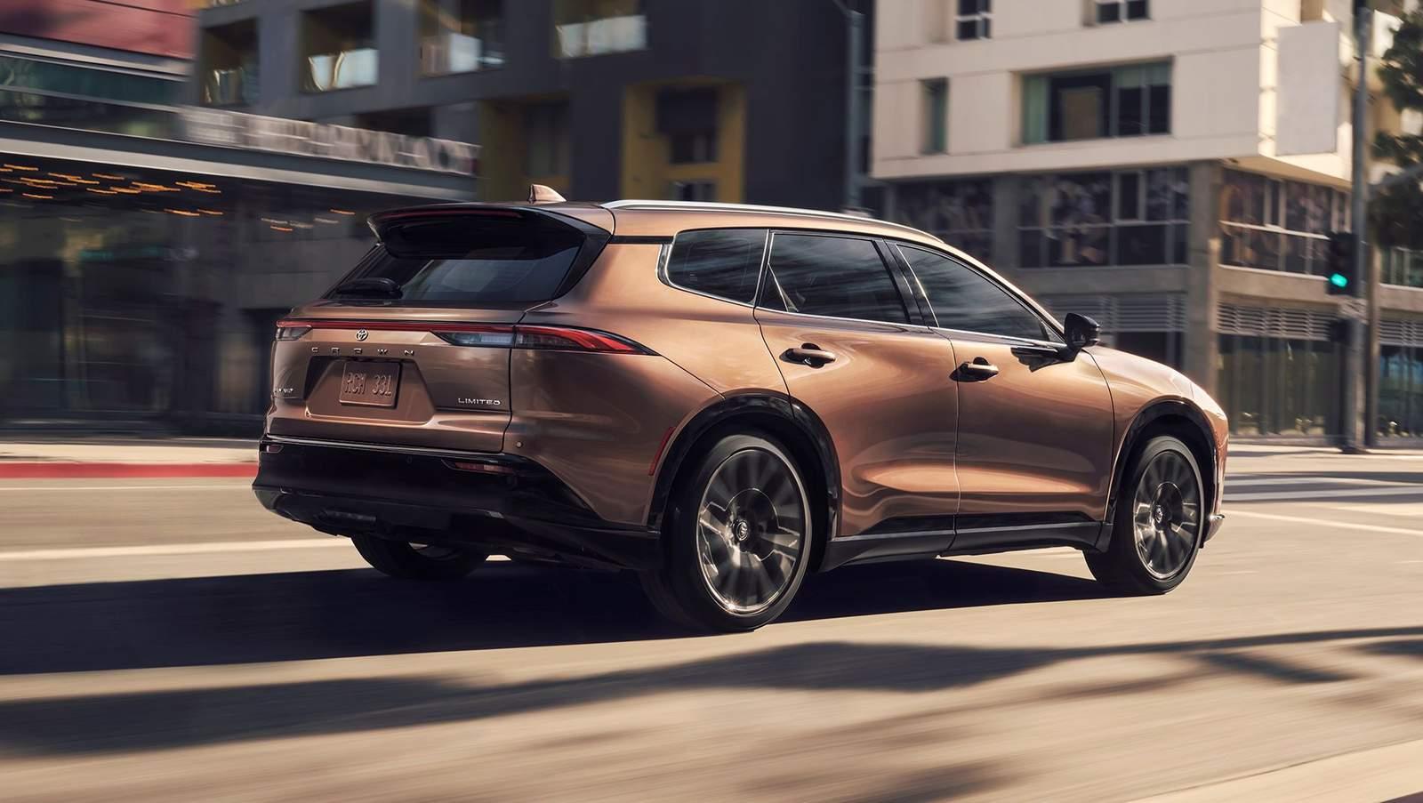 brown 2025 Toyota Crown Signia Hybrid driving down a city street