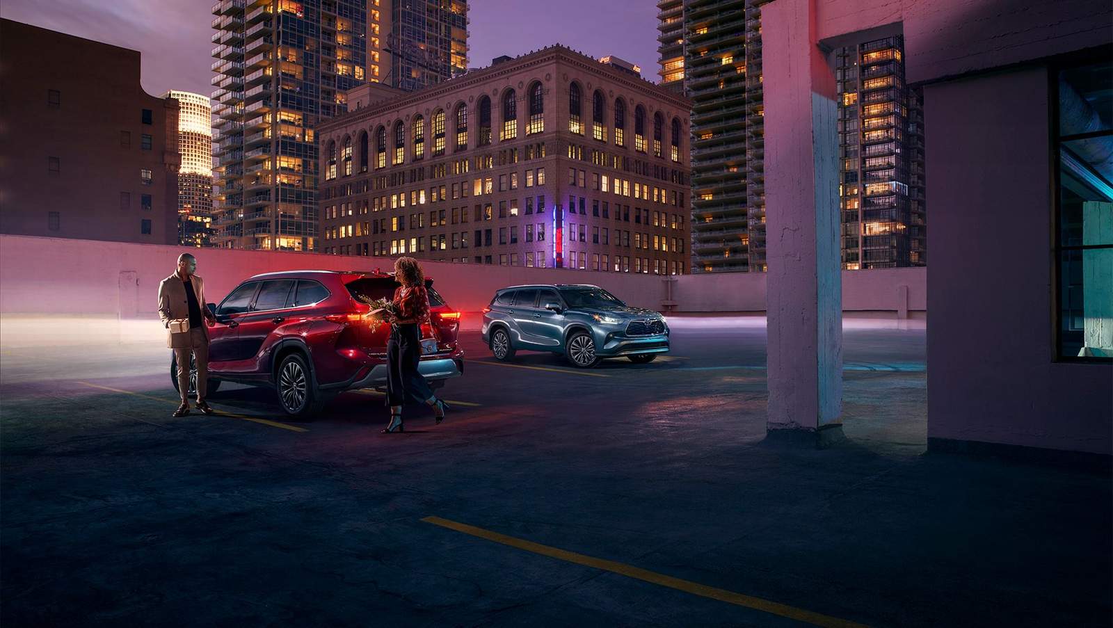 Night shot of 2 Toyota highlanders parked on the roof of a parking deck in a big city