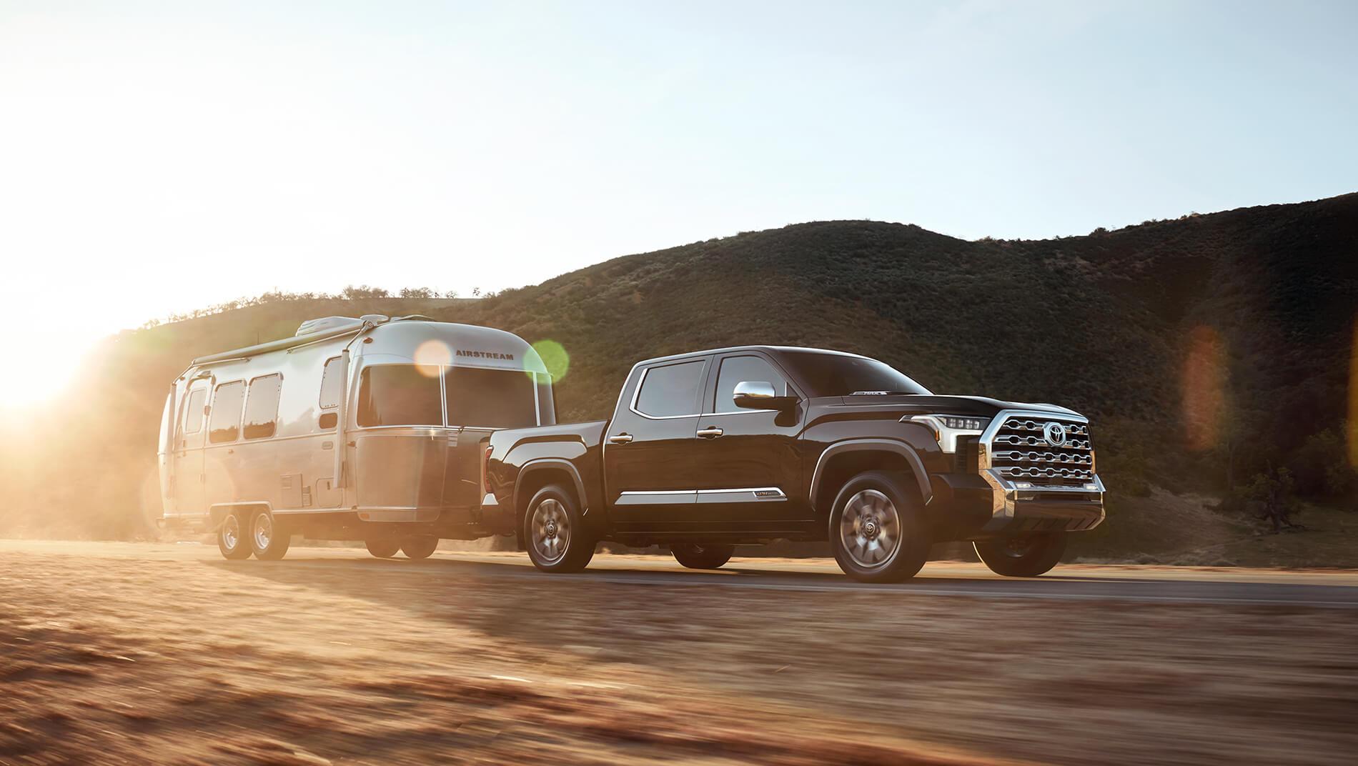 black Toyota Tundra pulling an airstream travel trailer in the mountains as the sun is going down