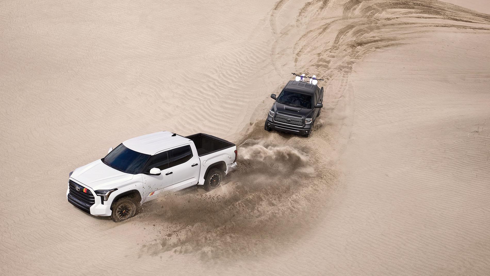 2 Toyota Tundra's, one black one white, driving in the desert.