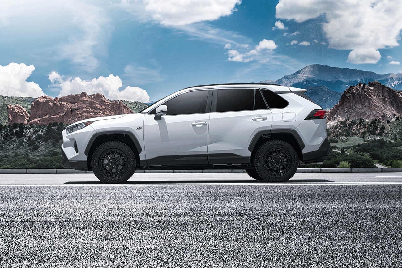 side view of a white Toyota RAV4 XP XSeries upgraded accessory package parked in front of the mountains