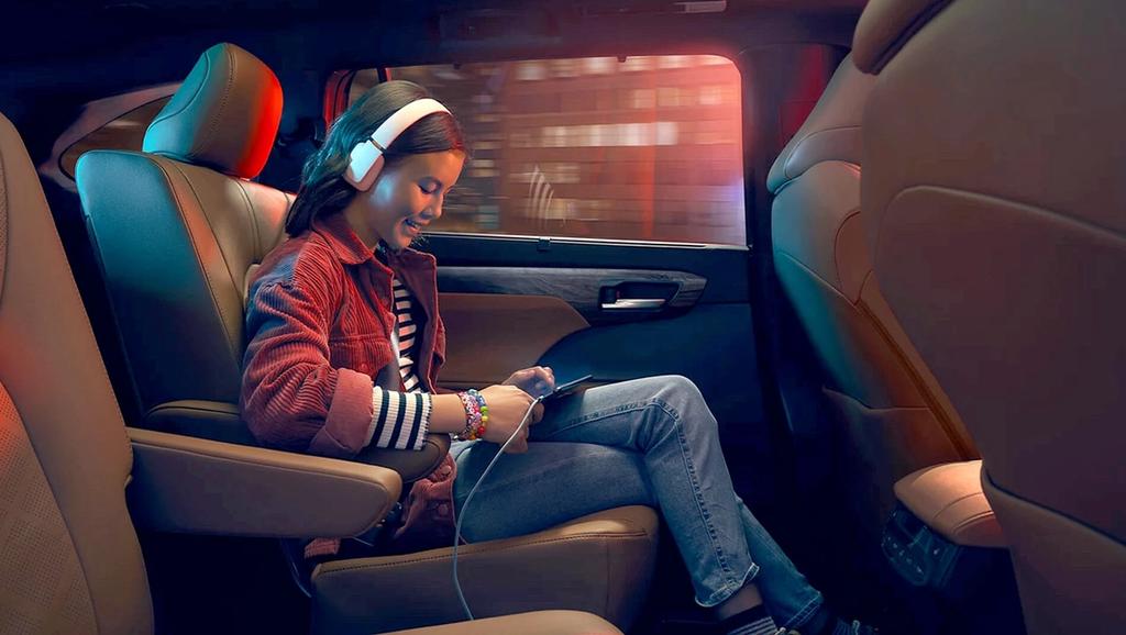 girl sitting in back seat of a Toyota Highlander using her phone while charging it